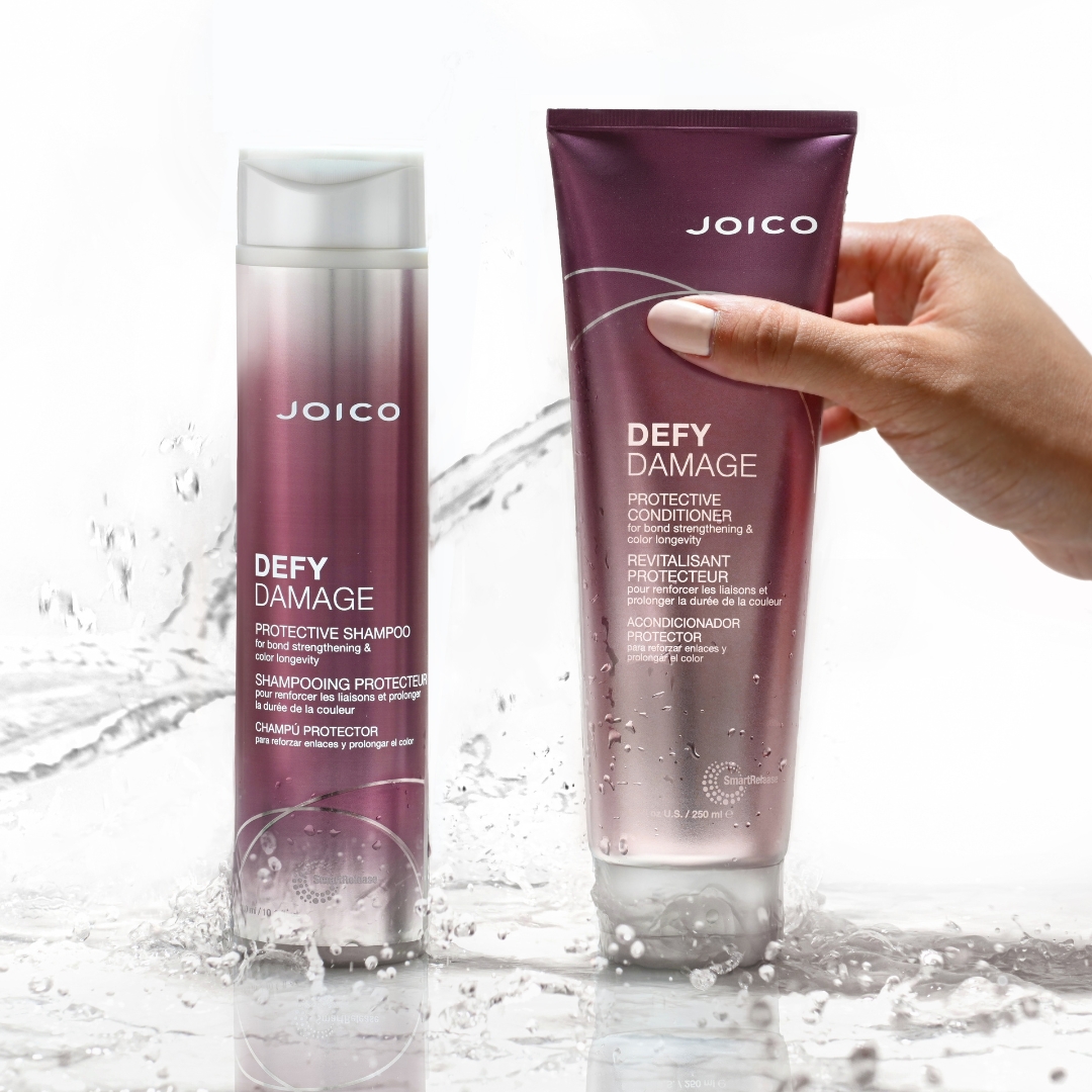 defy damage shampoo and conditioner with water splashing and hand reaching for conditioner
