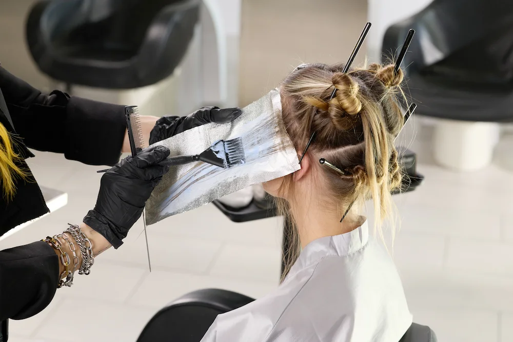 Hair color dye being applied with brush and foil